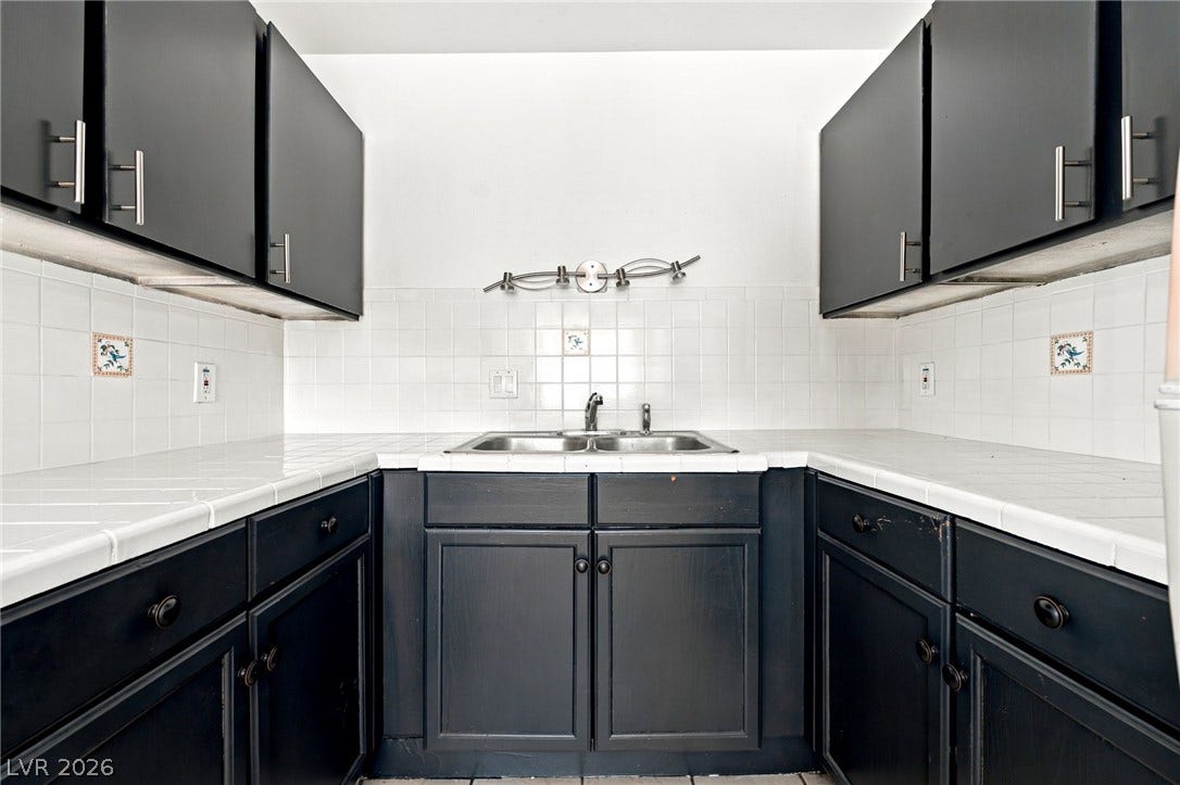 2553 Ellis Street, North Las Vegas, NV 89030 Dark cabinetry contrasts sharply with white tile countertops in this functional cooking space.