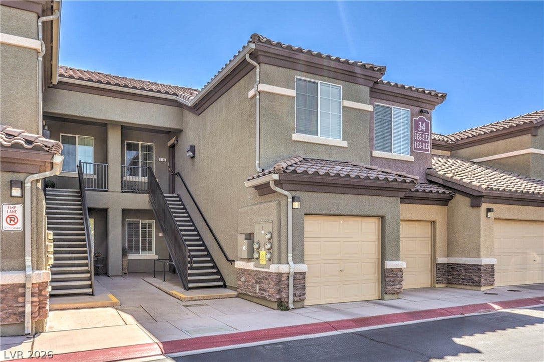 6868 Sky Pointe Drive, #1132, Las Vegas, NV 89131 Multi-level stucco exterior showcases built-in garage parking and stone-accented columns.