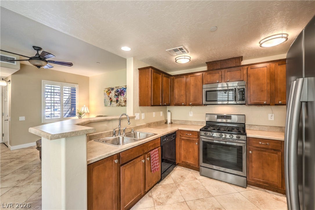 6868 Sky Pointe Drive, #1132, Las Vegas, NV 89131 Rich wood cabinetry paired with tile flooring defines this functional kitchen space.