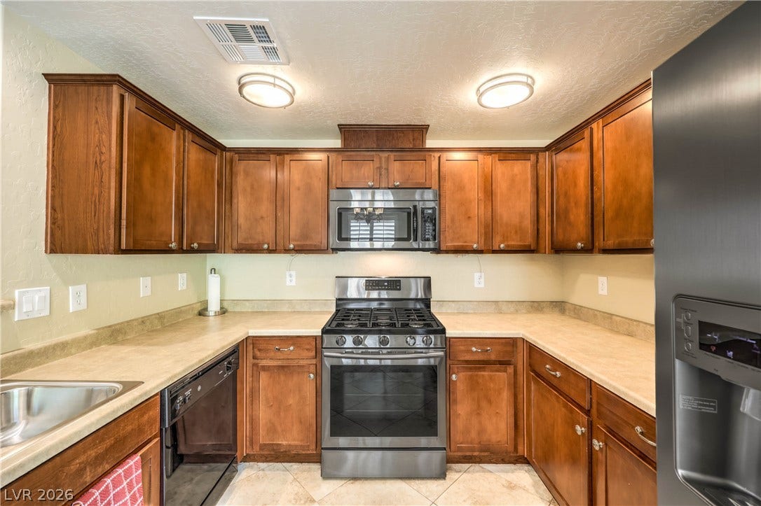 6868 Sky Pointe Drive, #1132, Las Vegas, NV 89131 Rich wood cabinetry surrounds integrated appliances above durable tile flooring in this efficient kitchen layout.
