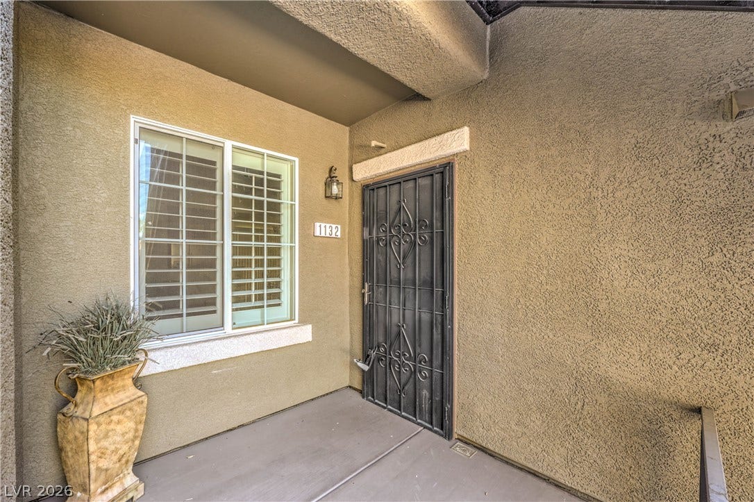 6868 Sky Pointe Drive, #1132, Las Vegas, NV 89131 A private covered entryway features durable stucco walls and a secure wrought iron screen door.
