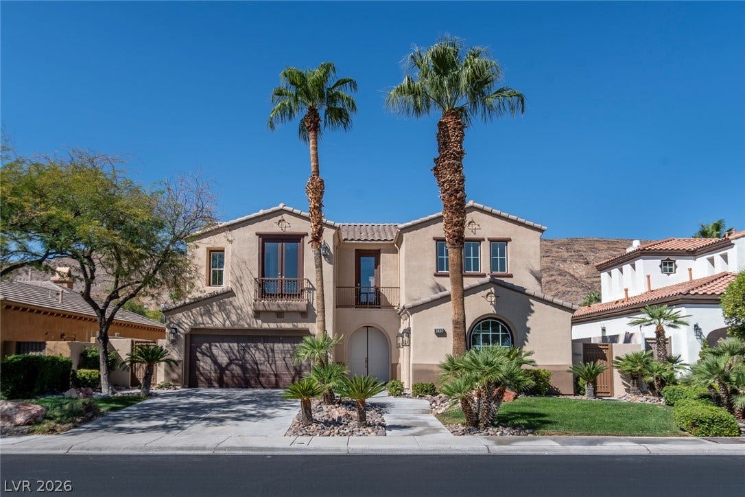 2837 Turtle Head Peak Drive, Las Vegas, NV 89135 Stately stucco architecture rises behind manicured tropical landscaping and towering palm trees.