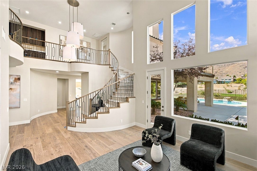 2837 Turtle Head Peak Drive, Las Vegas, NV 89135 A curved staircase and soaring walls of windows highlight this grand open living space.