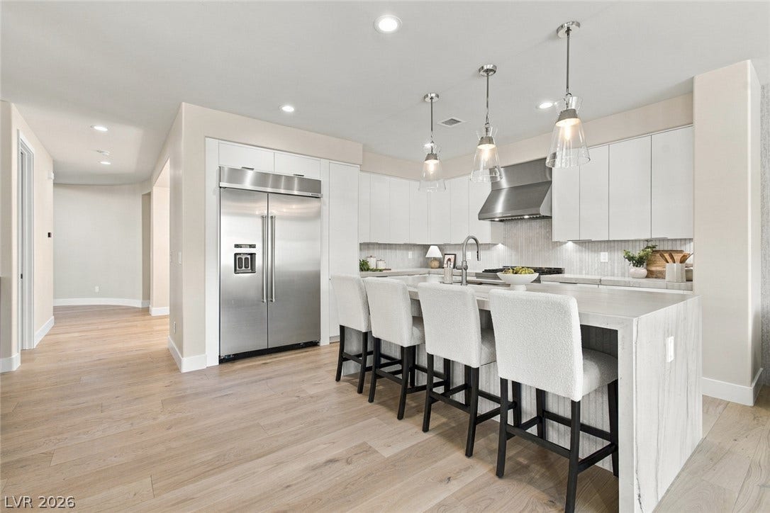 2837 Turtle Head Peak Drive, Las Vegas, NV 89135 A spacious culinary space highlights pale wood flooring alongside a waterfall stone island.