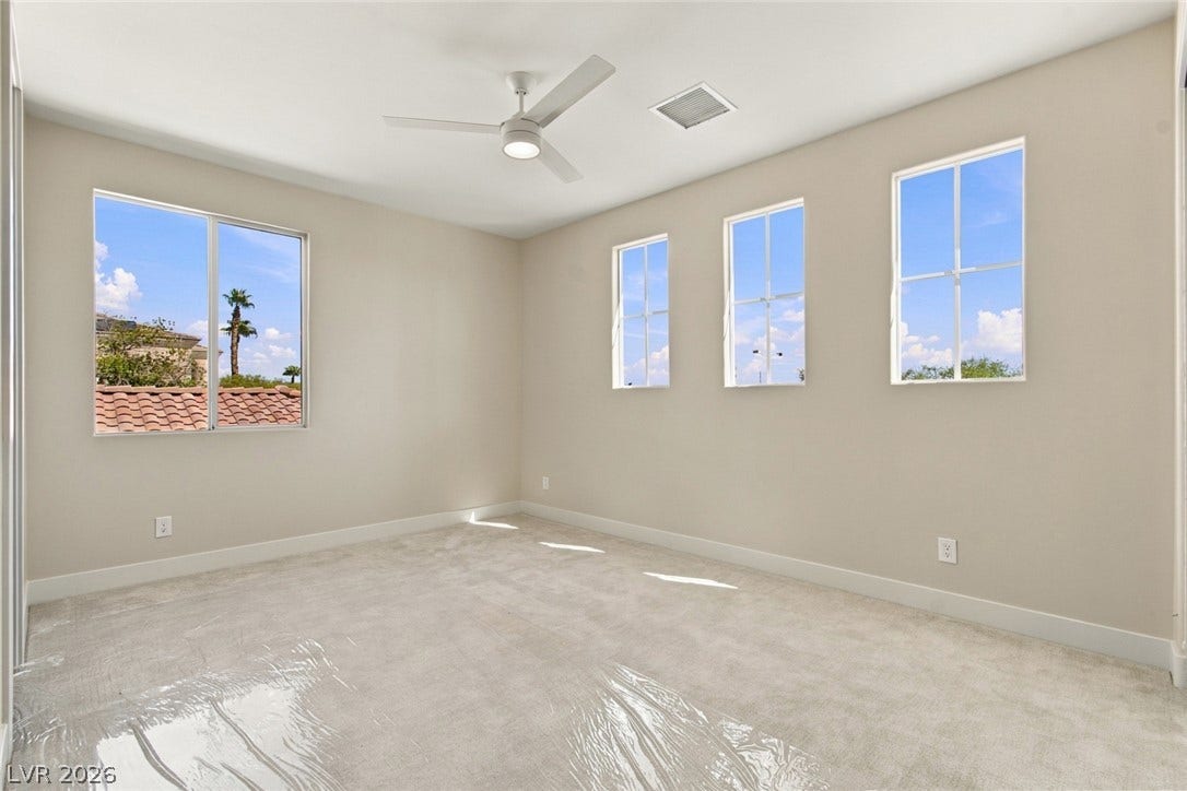 2837 Turtle Head Peak Drive, Las Vegas, NV 89135 Sunlight streams through multiple windows into this spacious bedroom featuring neutral walls and soft carpeting.