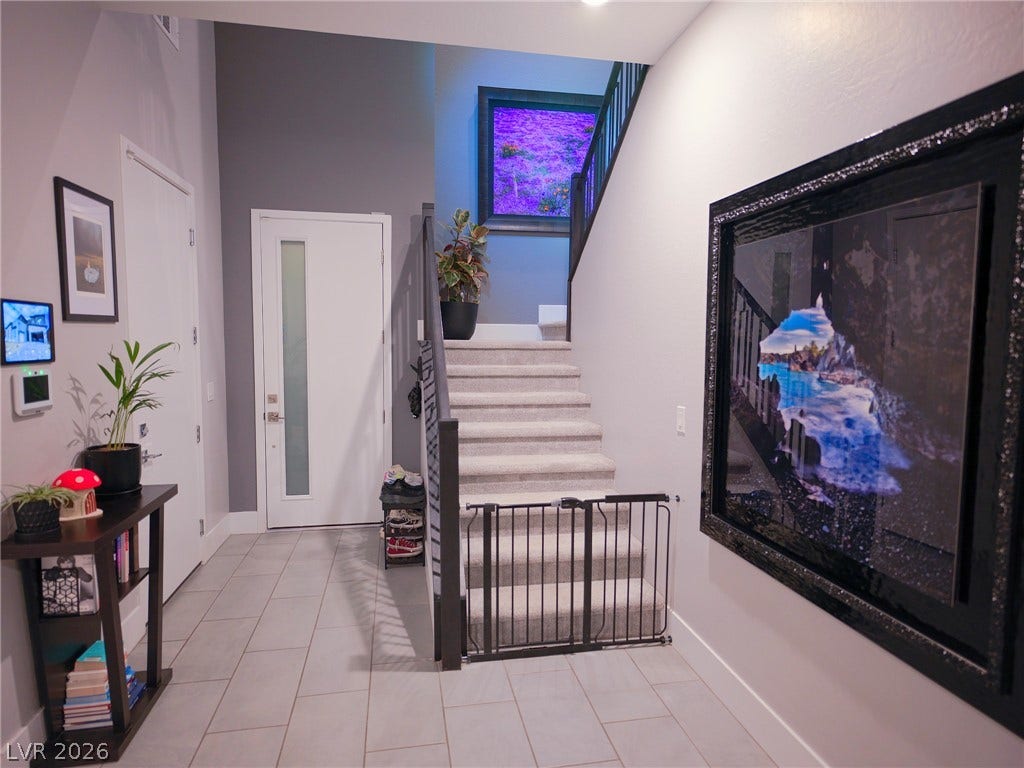 270 Shaded Canyon Drive, Henderson, NV 89012 A welcoming entryway features tile flooring, soaring ceilings, and carpeted stairs leading upward.