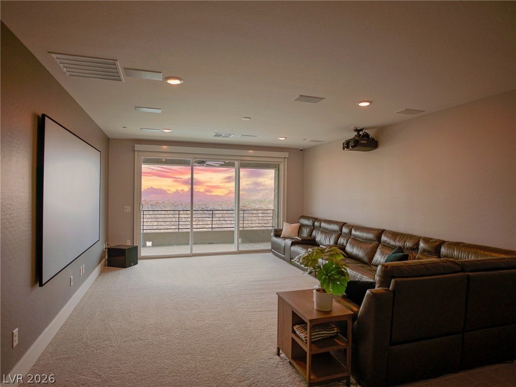 270 Shaded Canyon Drive, Henderson, NV 89012 Sliding glass doors frame sunset views in this carpeted home media room with recessed lighting.