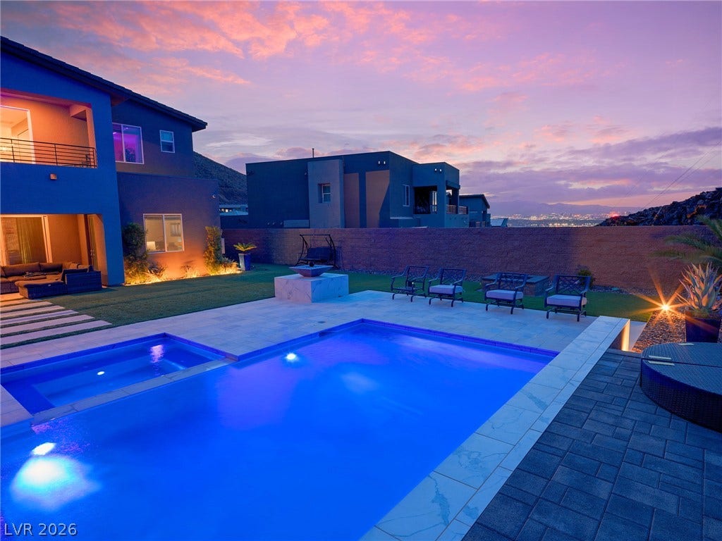 270 Shaded Canyon Drive, Henderson, NV 89012 A sparkling swimming pool highlights this tranquil backyard retreat under a vibrant evening sky.