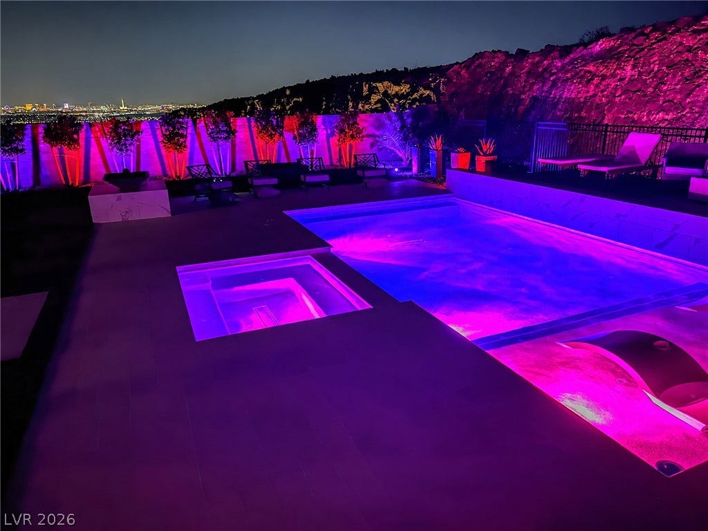 270 Shaded Canyon Drive, Henderson, NV 89012 Vibrant custom lighting illuminates the swimming pool and integrated spa under the evening sky.