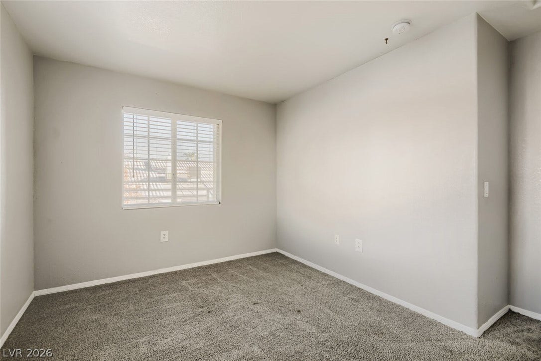 Plush carpeting and a classic window set a serene tone in this versatile bedroom.