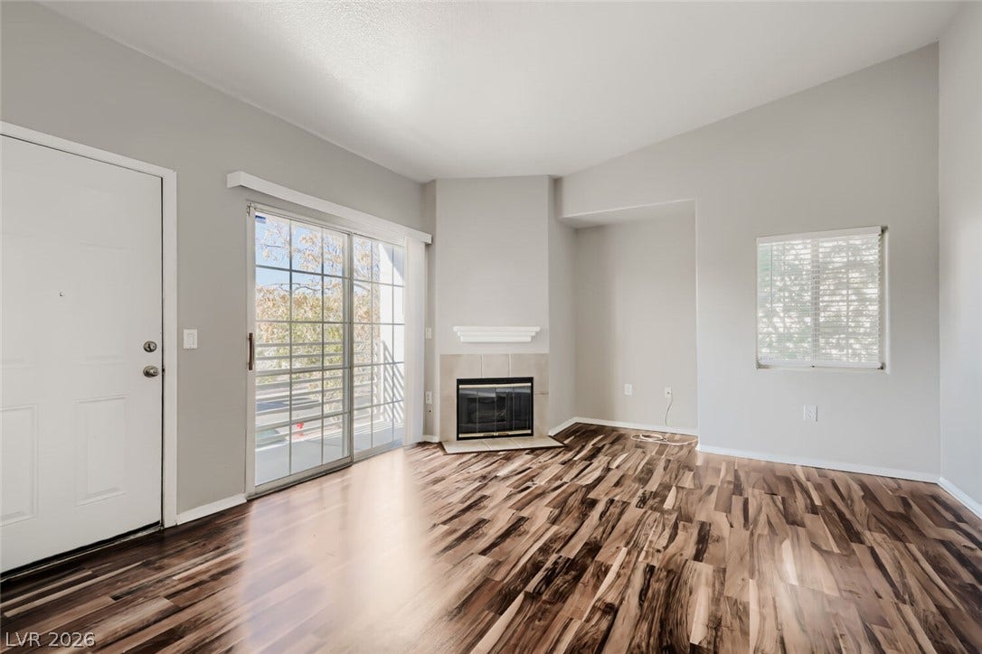 Rich wood flooring anchors this inviting living space anchored by a corner fireplace.