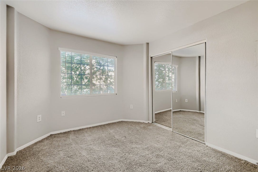 Mirrored sliding closet doors and neutral carpeting define this comfortable bedroom space.