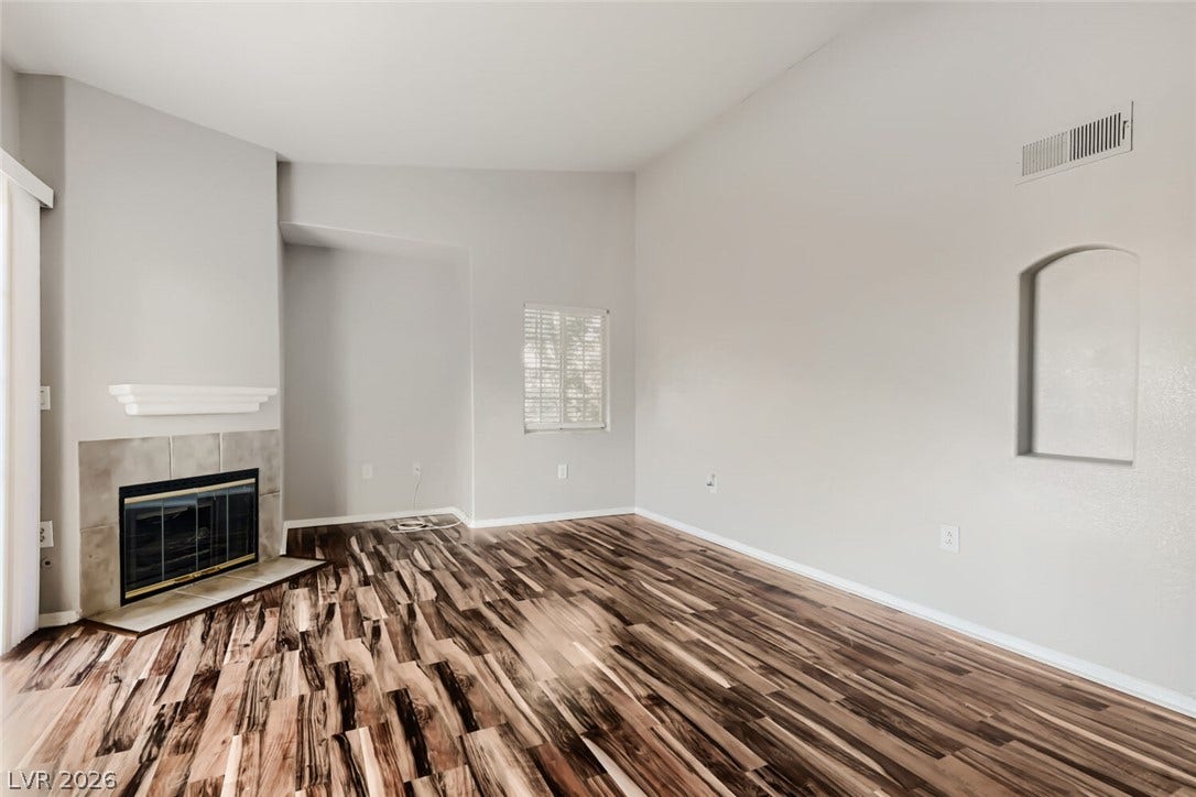 Richly grained wood flooring complements a classic tile-trimmed fireplace under vaulted ceilings.