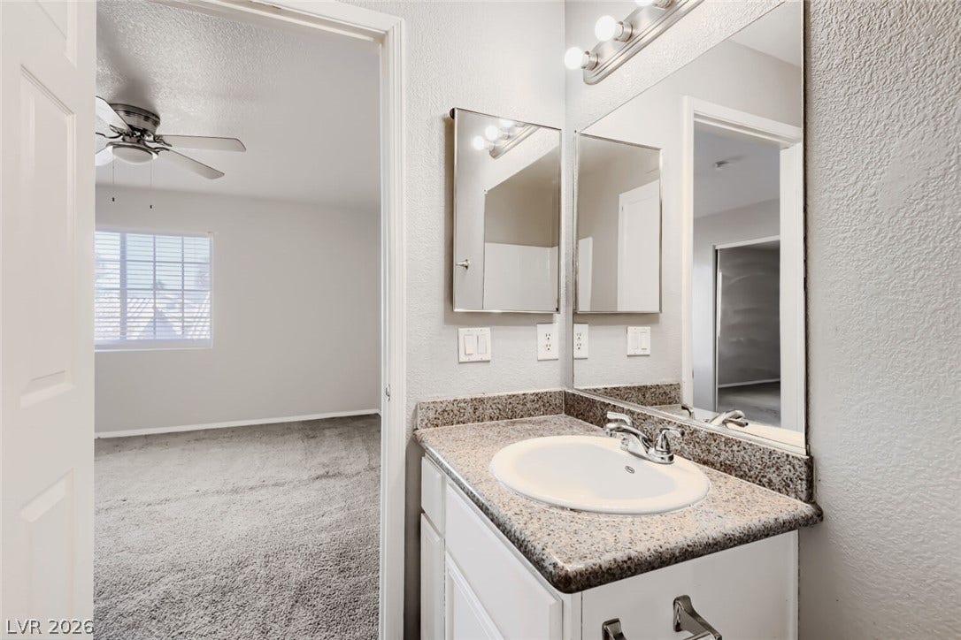Polished granite countertops complement the clean white cabinetry in this functional vanity area.