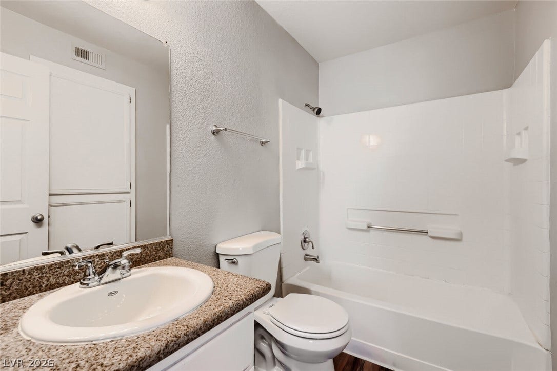 Polished stone counters and a clean tub surround define this classic full bathroom.