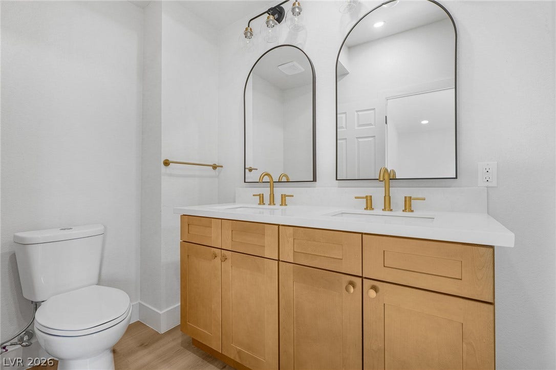 A contemporary dual-sink vanity sits beneath arched mirrors in this clean bathroom design.