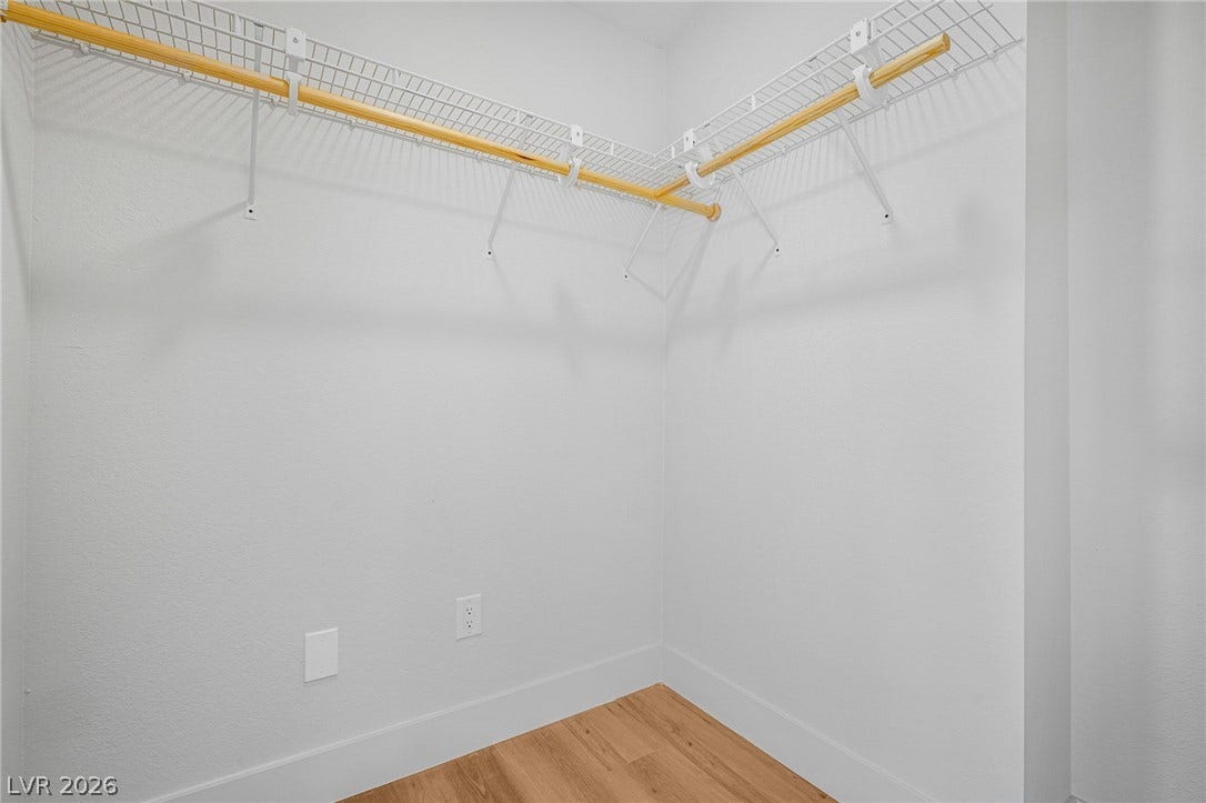 Functional wire shelving and hanging rods maximize storage space above smooth wood-toned flooring.