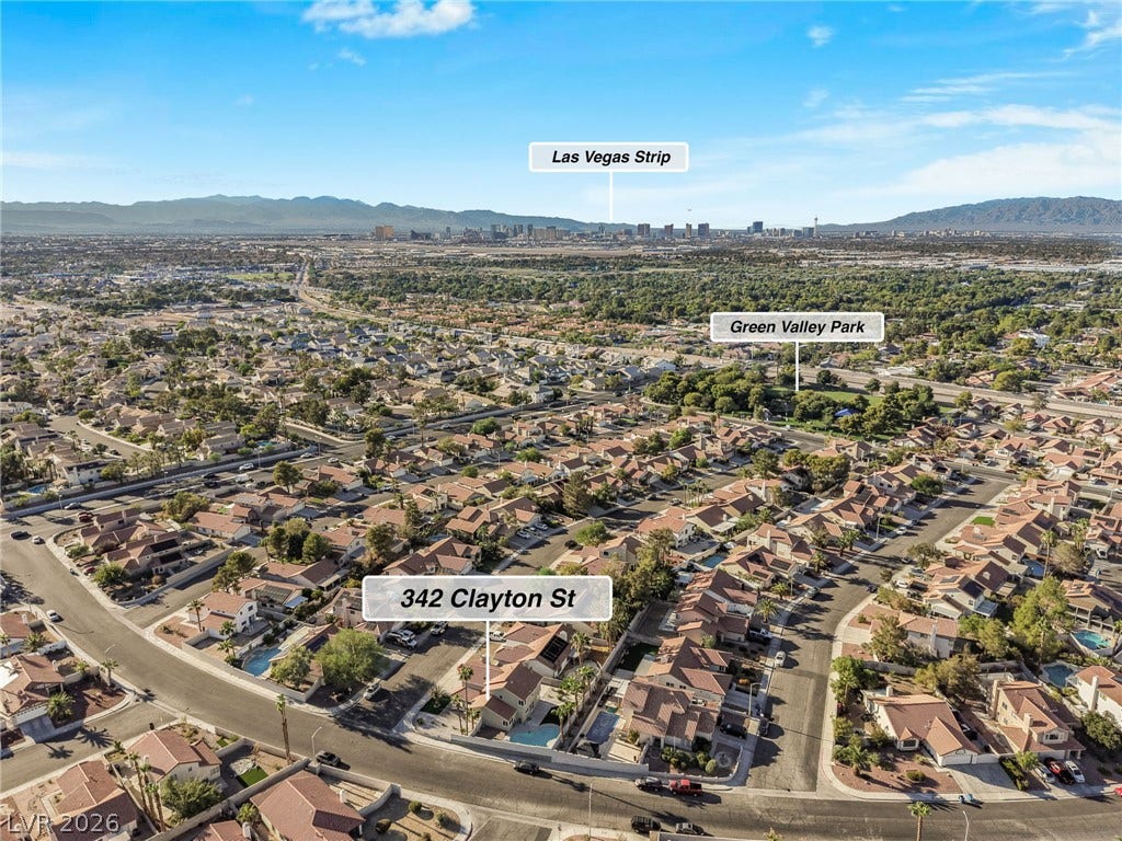 An aerial perspective captures the neighborhood and distant city skyline under wide open desert skies.