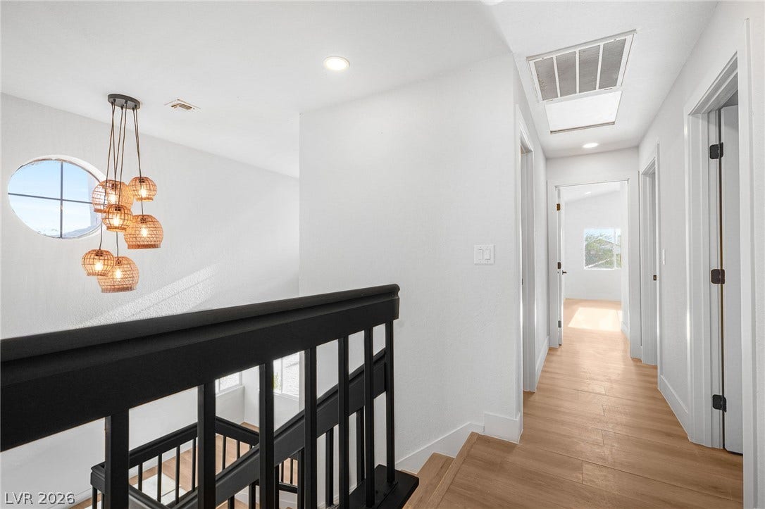 Crisp white walls and warm wood-style flooring define this bright upper-level hallway landing.