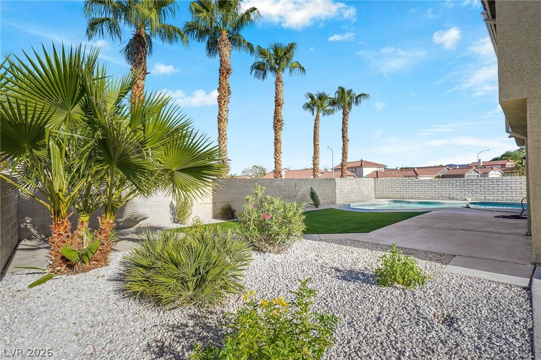 Towering palm trees and low-maintenance desert landscaping frame a refreshing private backyard swimming pool.