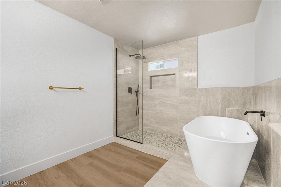 A glass-enclosed walk-in shower and freestanding tub elevate this serene, modern bathroom.
