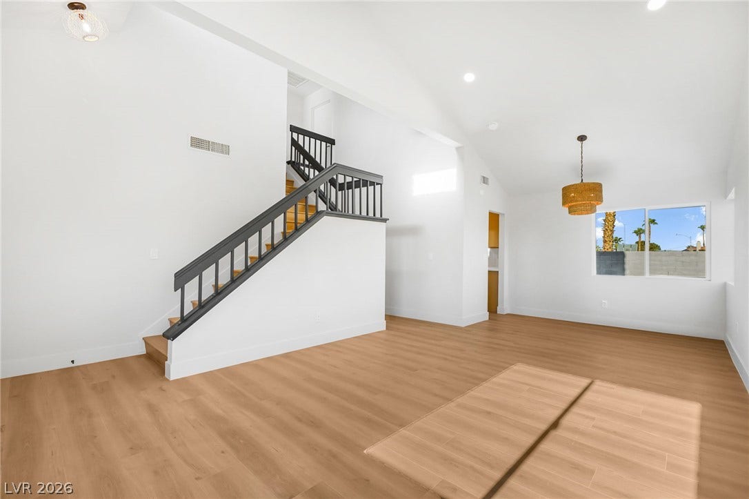 A spacious living area displays soaring vaulted ceilings and a clean contemporary staircase.