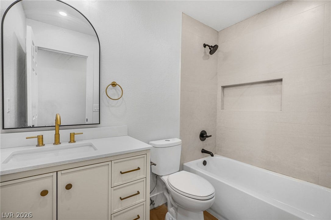 A modern bathroom features a tiled tub surround and clean vanity lines.