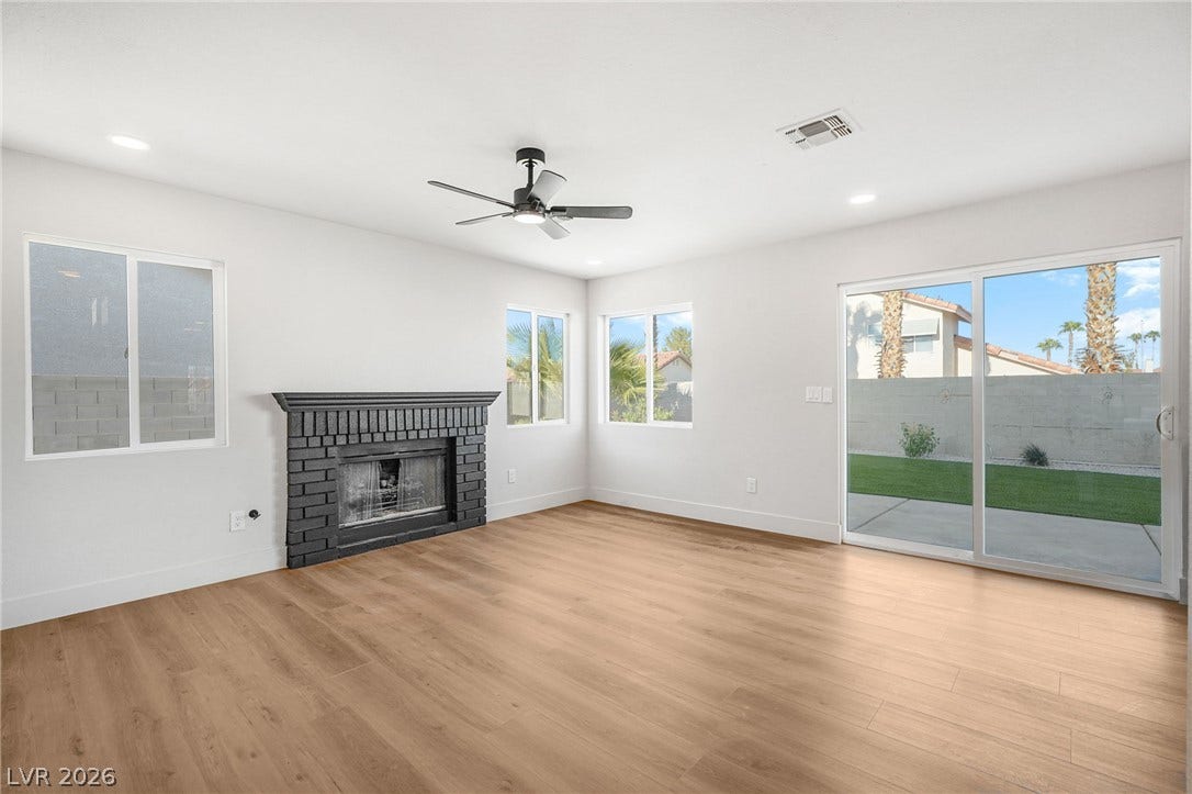 Warm wood-style floors anchor this airy living space complete with a classic brick fireplace.