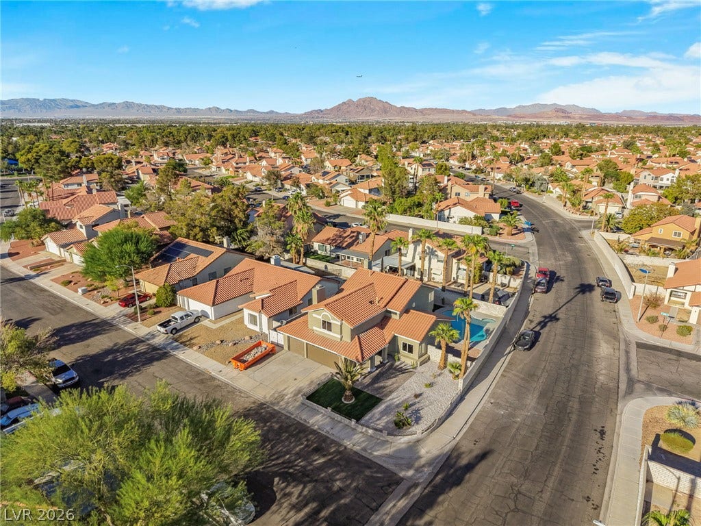 Distant mountain ranges frame a quiet residential neighborhood featuring tile roofs and private pools.