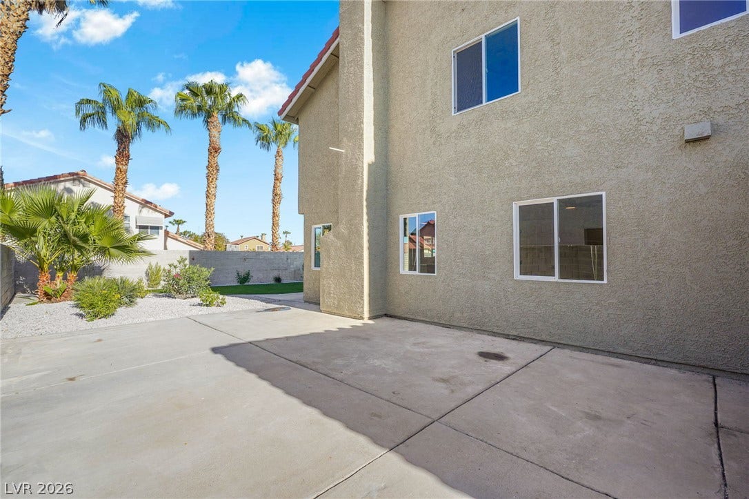 Concrete patio areas line the rear exterior of this multi-level stucco home.