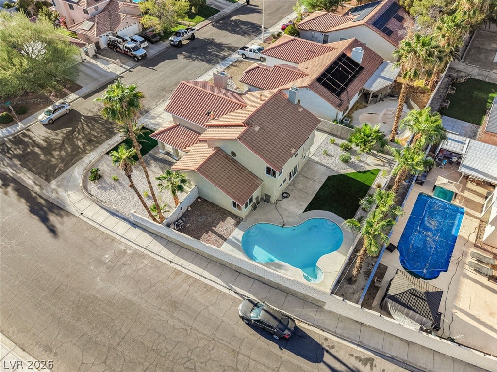 An aerial perspective showcases a tile roof home featuring a private backyard swimming pool.