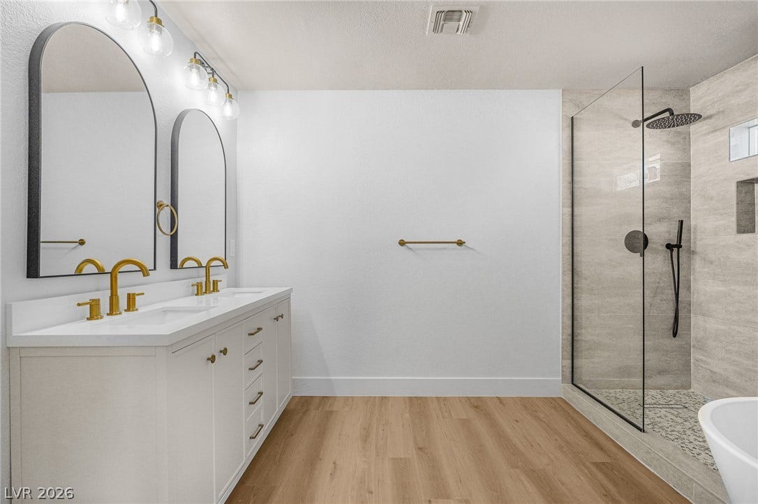 Clean lines and warm wood floors define this updated bathroom featuring a glass-enclosed shower.