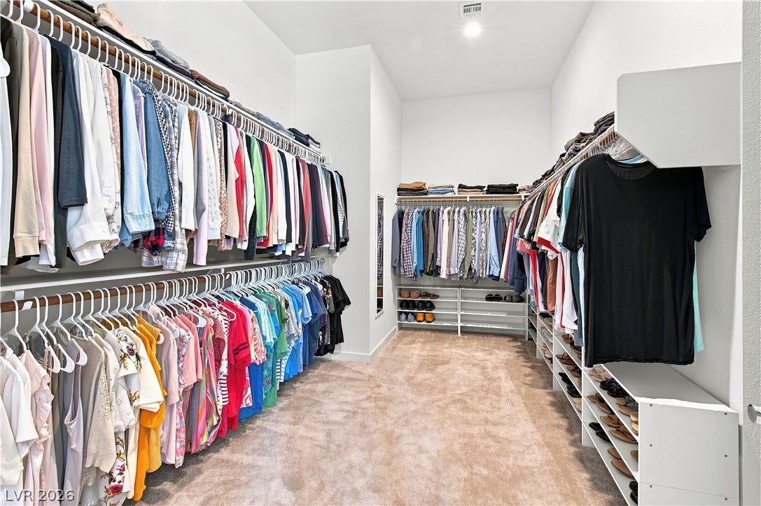 5745 N Golden Chase Court, Las Vegas, NV 89131 A spacious walk-in closet features abundant hanging rods, integrated shelving, and soft carpeting.