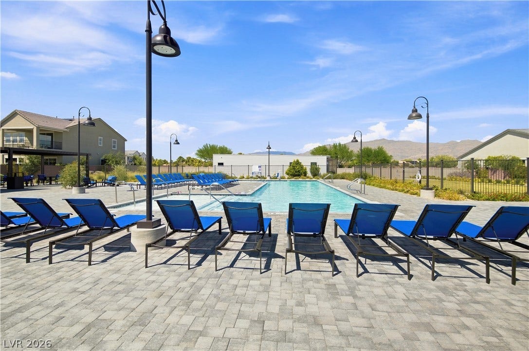 5745 N Golden Chase Court, Las Vegas, NV 89131 A spacious stone paver deck surrounds a sparkling community swimming pool under blue skies.