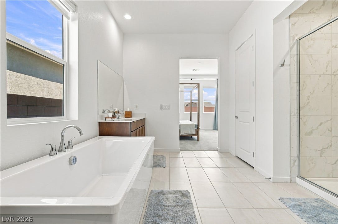 5745 N Golden Chase Court, Las Vegas, NV 89131 A deep soaking tub and tile floors anchor this modern master bathroom retreat.