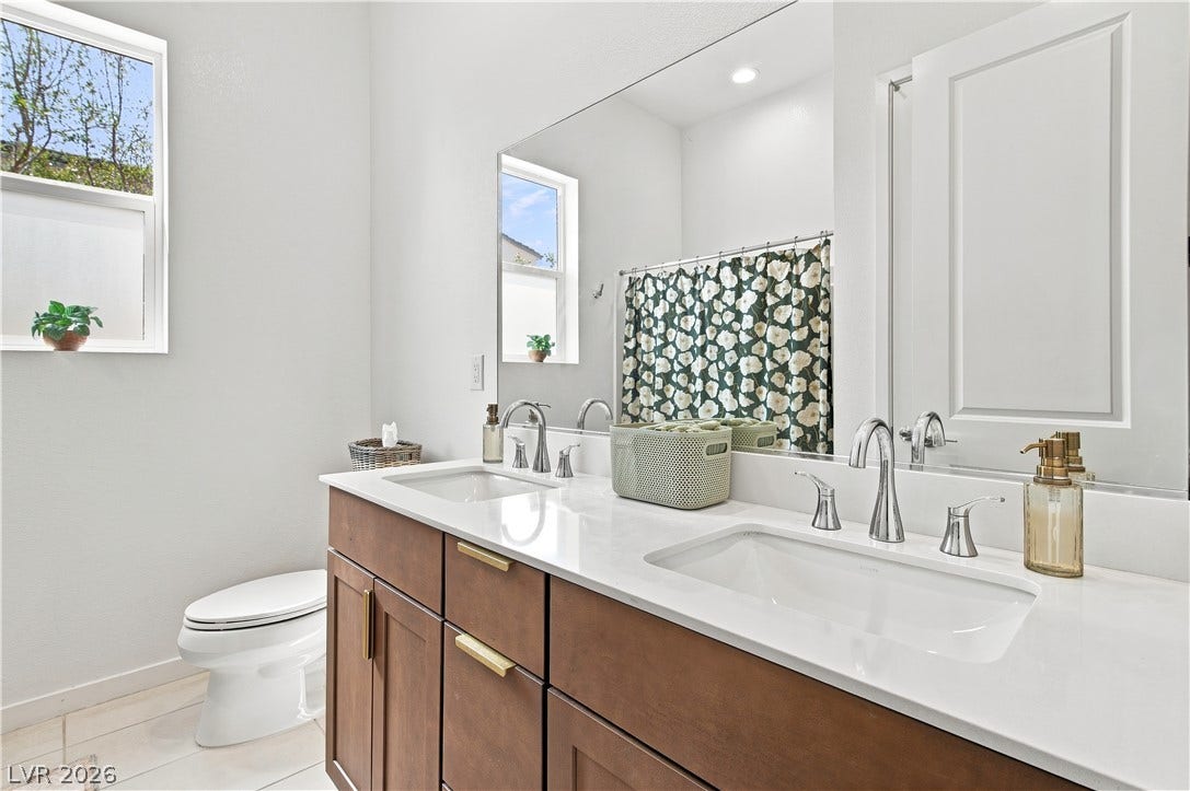 5745 N Golden Chase Court, Las Vegas, NV 89131 A contemporary vanity setup with dual under-mount sinks and clean stone countertops.