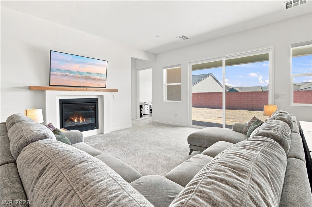 5745 N Golden Chase Court, Las Vegas, NV 89131 Sliding glass doors open to the backyard from this comfortable living space with a fireplace.
