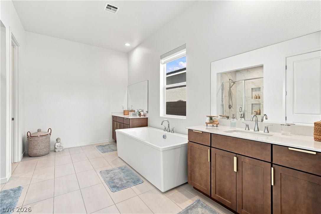 5745 N Golden Chase Court, Las Vegas, NV 89131 Tiled flooring and a modern soaking tub define this pristine, light-filled bathroom space.