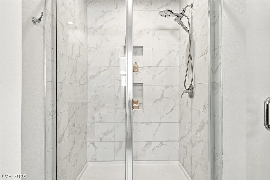 5745 N Golden Chase Court, Las Vegas, NV 89131 Elegant tilework and modern fixtures define this glass-enclosed walk-in shower.