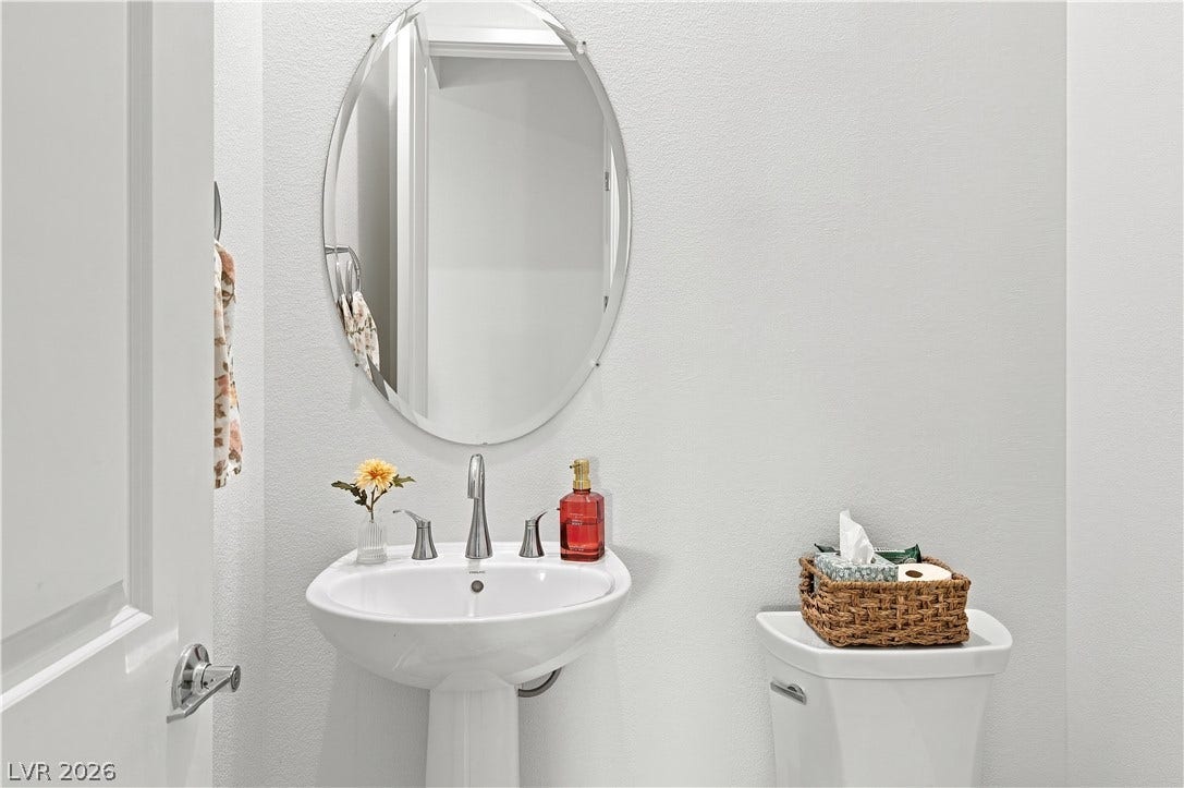 5745 N Golden Chase Court, Las Vegas, NV 89131 A classic pedestal sink stands beneath an oval mirror in this clean powder room.