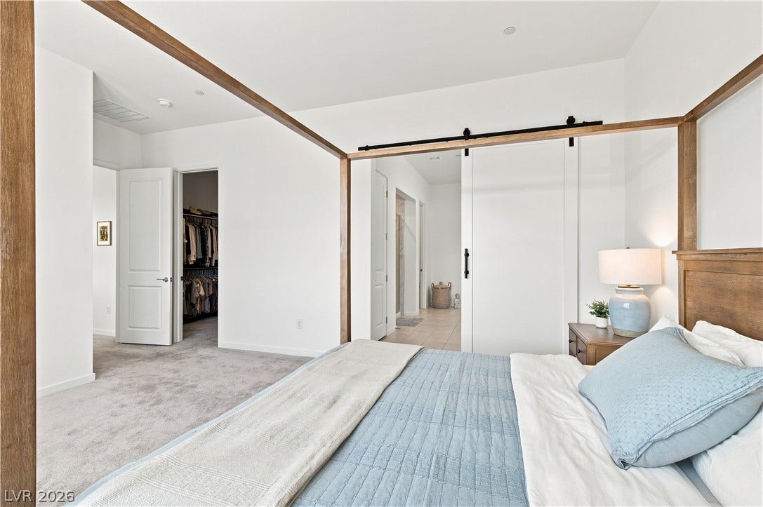 5745 N Golden Chase Court, Las Vegas, NV 89131 A spacious bedroom showcases plush carpeting, high ceilings, and a sliding barn door entry.