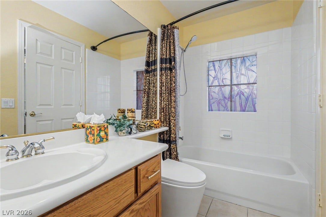 Tiled walls and a classic wood vanity complete this functional full bathroom.