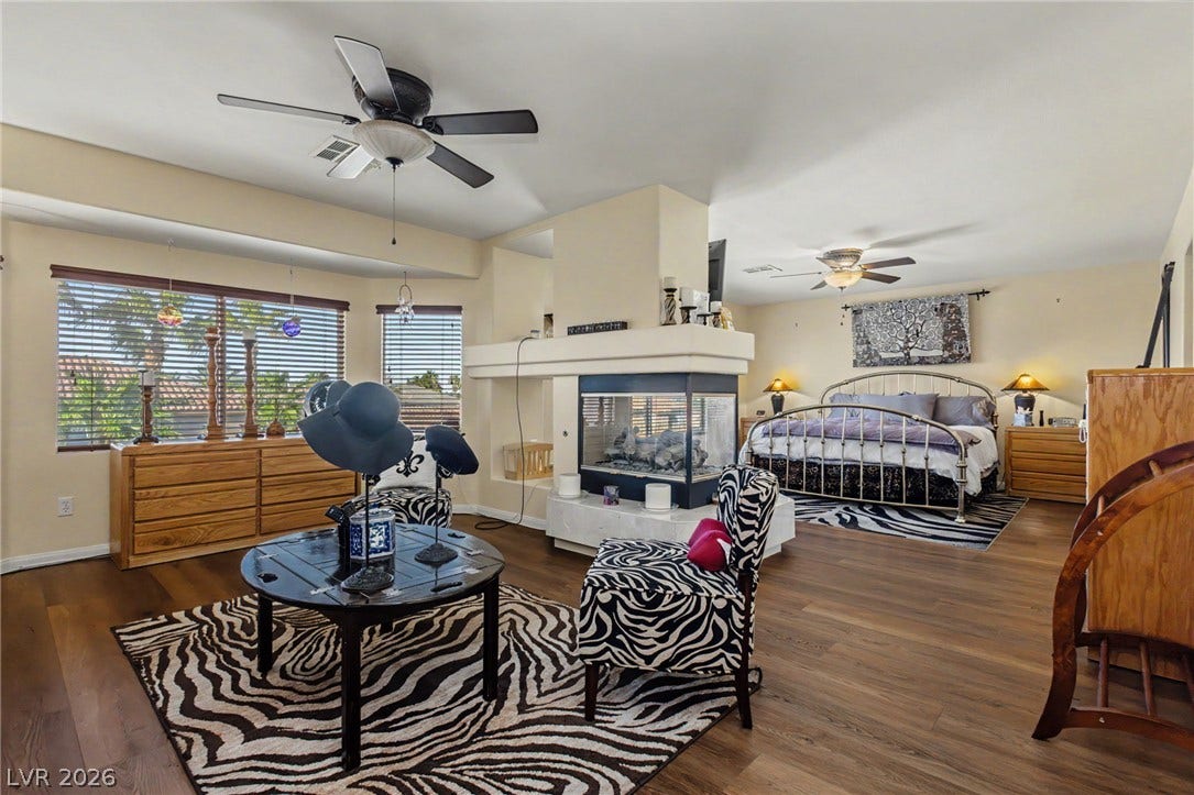 An open bedroom suite with warm wood flooring and a modern three-sided fireplace.