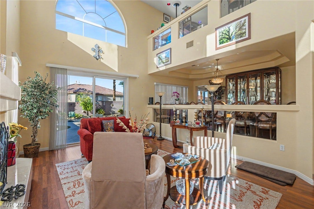 Dramatic high ceilings and a massive arched window illuminate this open-concept living space.