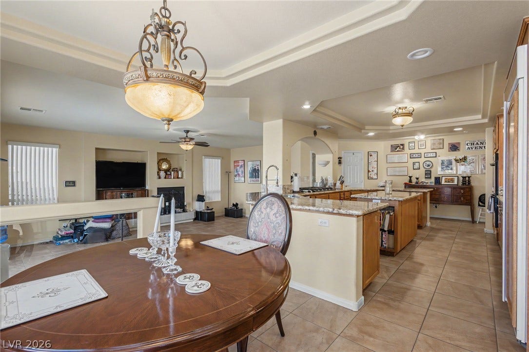 Tile flooring and a tray ceiling flow throughout the open concept kitchen and dining space.