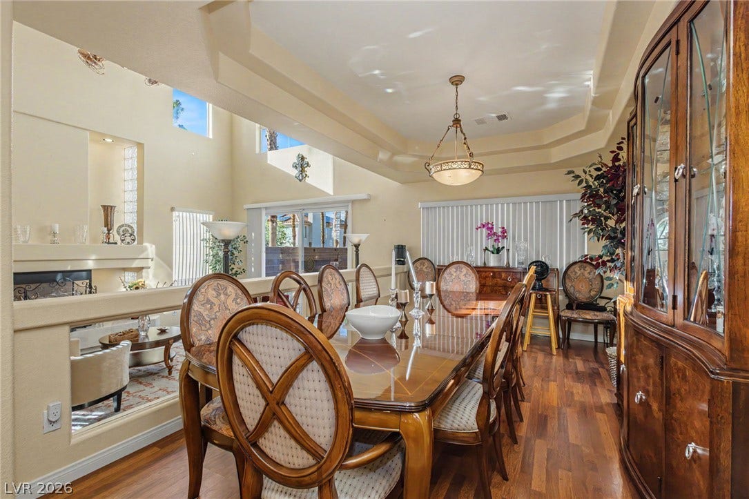 Rich hardwood flooring pairs beautifully with a tray ceiling in this open dining room.