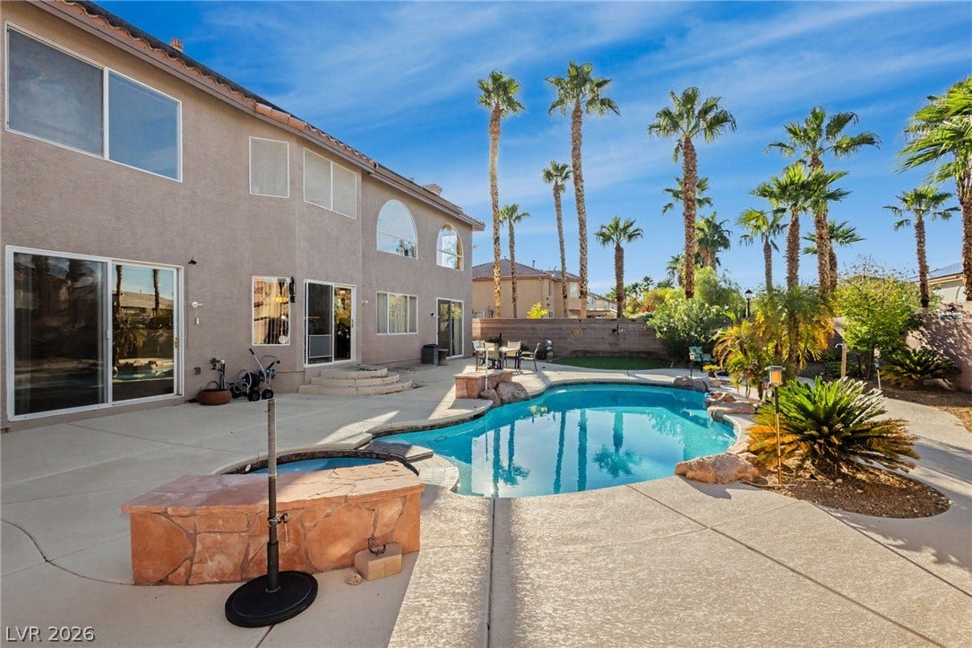 A sparkling swimming pool highlights this backyard oasis framed by soaring palm trees.