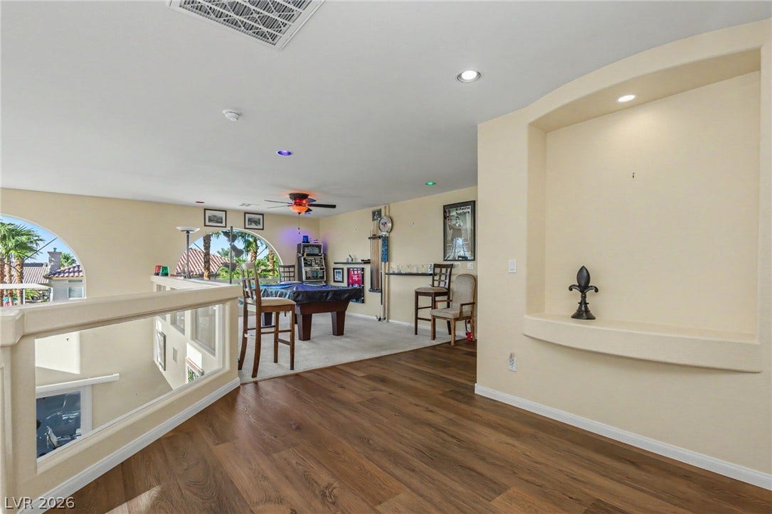 An upper-level loft transitions seamlessly from wood flooring to a carpeted recreation area.