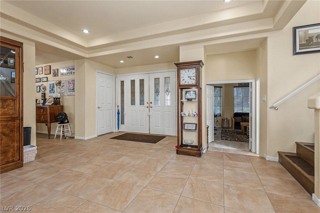 Double doors open into a tiled entryway featuring a classic tray ceiling.