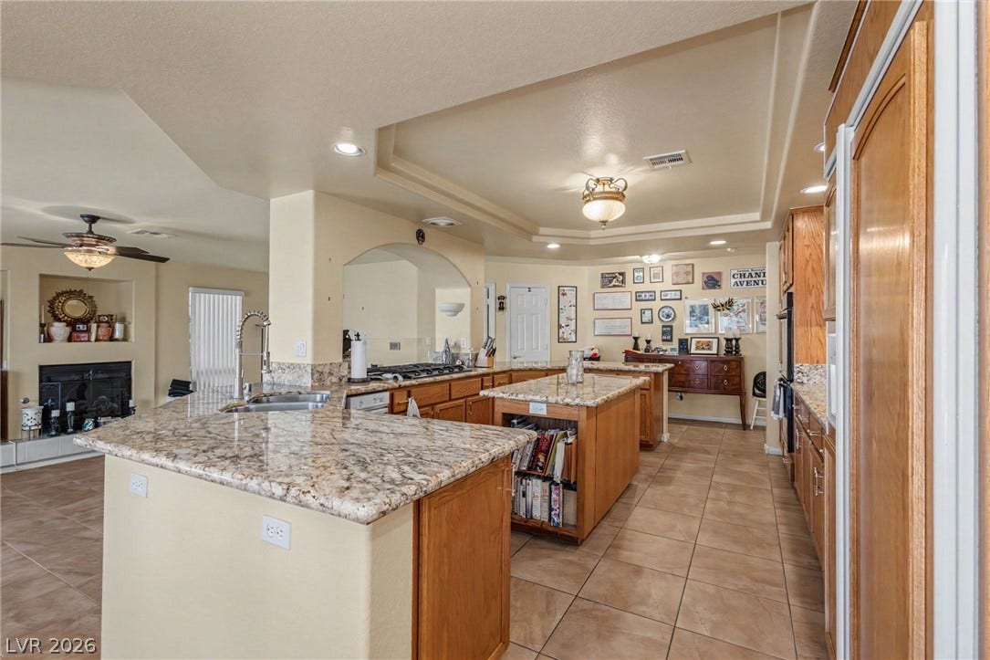 Polished granite countertops complement warm wood cabinetry in this sprawling cooking space.